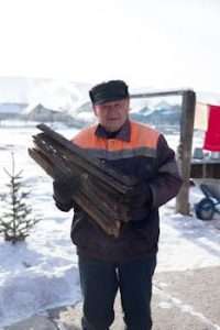 An Elderly Man Carrying Chopped Wood