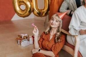 Senior woman celebrating her 60th birthday with joy and gifts indoors.