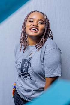 Happy woman with braided hair wearing a casual t-shirt, smiling brightly.