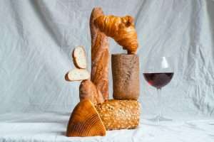 Creative still life of assorted breads with a glass of red wine.