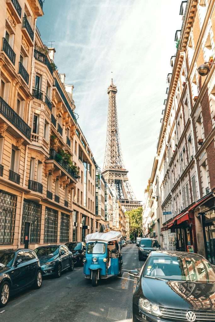Charming Parisian street scene with the Eiffel Tower, cars, and classic architecture.