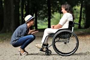 Two women enjoy a lively conversation in a sunny park, embracing friendship and happiness.