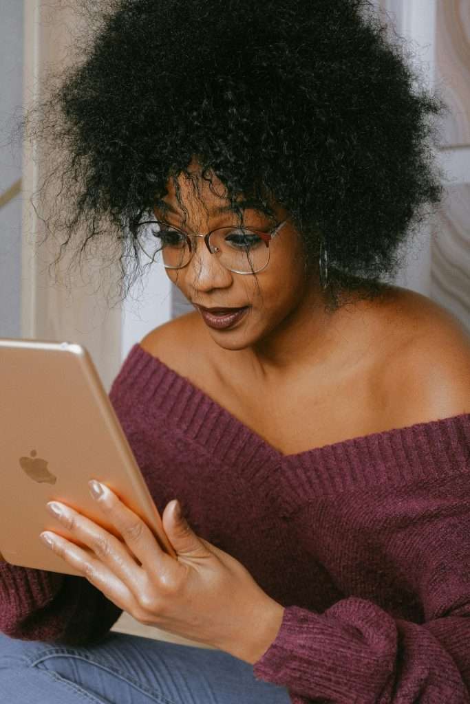 Portrait of a woman with an afro reading from a tablet indoors, immersed in technology.