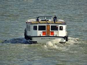 A boat named Hollywood navigating the waters of the River Thames in London.