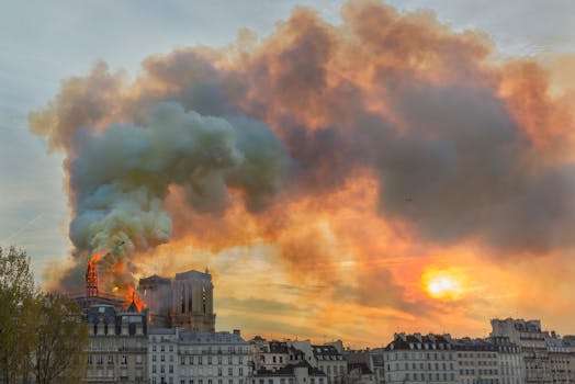 Smoke billows from Notre Dame Cathedral as it burns during sunset in Paris, France.