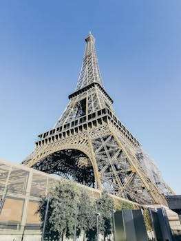 Low angle view of the iconic Eiffel Tower in Paris with a clear blue sky backdrop.